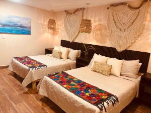 een kamer met twee bedden met kleurrijke kussens erop bij Villa Lol Tun Breakfast and Beach Club Included in Isla Mujeres +80 foto's