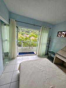 a bedroom with a bed and a large window at Acomodação Recanto do Sameiro in Mongaguá