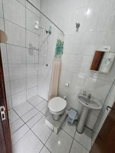 a bathroom with a shower and a toilet and a sink at Acomodação Recanto do Sameiro in Mongaguá