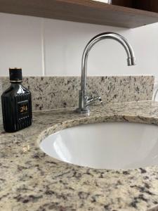 Un mostrador de baño con un lavabo y una botella de jabón. en NoiZ Apartment - SofaHouse, en Rio das Ostras