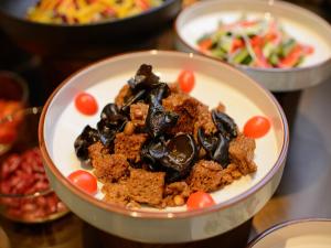 eine Schüssel mit Essen auf einem Tisch mit anderen Tellern mit Essen in der Unterkunft Orange Hotel Shanghai New International Expo Centre in Shanghai