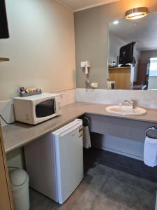 a bathroom with a microwave on a counter with a sink at Landmark Manor in New Plymouth +36 photos