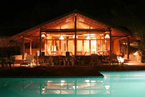 a pavilion with chairs and a pool at night at Pousada do Quilombo in São Bento do Sapucaí