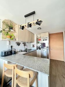 a kitchen with a counter and two stools in it at Departamento céntrico nuevo in Valdivia +2 photos