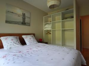 - une chambre avec un lit blanc orné de fleurs rouges dans l'établissement Appartement accessible PMR avec jardin et parking couvert, proche des pistes - FR-1-858-8, à Mont-Dore