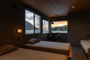 a bedroom with two beds and a large window at TATARA FACTORY stay in Imabari