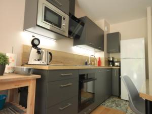 - une cuisine avec des placards gris et un four micro-ondes dans l'établissement Charmant appartement scandinave avec parking au Mont-Dore - FR-1-858-1, à Mont-Dore 5 autres photos