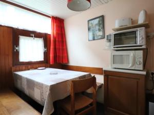 a kitchen with a table and a microwave at Charmant Duplex 4 Pers. avec Parking Privé à Murat-le-Quaire - FR-1-858-9 in Murat-le-Quaire