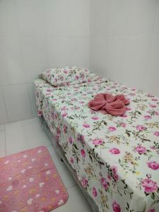 a bed with a flowery sheet and two pillows on it at Quarto para solteiro perto do aeroporto e parques in Belém