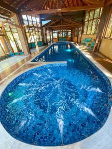 a large swimming pool with blue water in a building at Espaço Tajj in São Roque