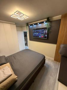 BC Apartamento alto padrão de 2 quartos com Garagem في باليريو كامبوريو: غرفة بها سرير وتلفزيون على الحائط