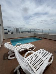 a white lounge chair next to a swimming pool at Apartamento Monoambiente en Encarnación con Parking in Encarnación