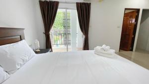a white bed with a pair of white shoes on it at The Nap House Phuket Town in Phuket Town +4 photos