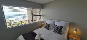 a bedroom with a bed with two pillows and a window at 59 De Valle, Diaz Beach in Mossel Bay