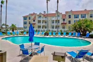 a pool with chairs and a table and a building at Island Palms - 2 min walk to the Beach in Corpus Christi