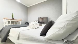 a bedroom with a white bed with towels on it at Cantinho Perfeito para Dois Conforto e Mar Bem Pertinho, Casa terrea no centro 80M Praia, Ar, Enxoval,Estacionamento e churrasqueira in Itanhaém