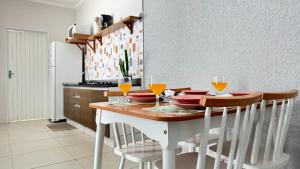 a kitchen with a table with glasses of orange juice at Cantinho Perfeito para Dois Conforto e Mar Bem Pertinho, Casa terrea no centro 80M Praia, Ar, Enxoval,Estacionamento e churrasqueira in Itanhaém