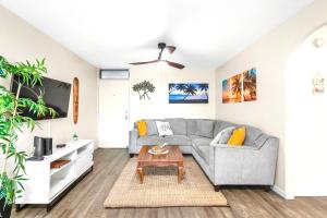 Una sala de estar con un sofá gris y una mesa. en Kalama Terrace 2BR with Pool, BBQ, AC & Walk to the Beach, en Kihei