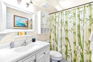 Un baño con lavabo y cortina de ducha con bambú. en Kalama Terrace 2BR with Pool, BBQ, AC & Walk to the Beach, en Kihei