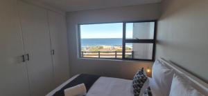 a bedroom with a view of the ocean from a window at 59 De Valle, Diaz Beach in Mossel Bay
