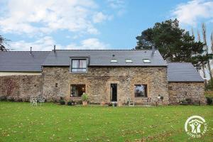 a large stone house with a large yard at Fontaine aman in La Roche-Derrien