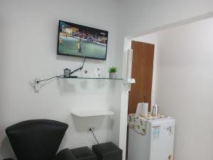 ein Zimmer mit einem Fernseher an der Wand und einem Kühlschrank in der Unterkunft At Suites in Maragogi