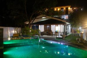a swimming pool in front of a house at night at Sea Bloom Villa in Kamburugamuwa