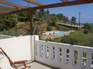 a balcony with a chair and a swimming pool at Vassiliki Studios in Andros