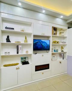 un soggiorno con scaffali bianchi e TV di Casa Azul Serin East Tagaytay a Tagaytay Altre 15 foto