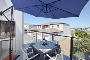 a blue table and chairs on a balcony with an umbrella at sandytoesatbigbay in Cape Town