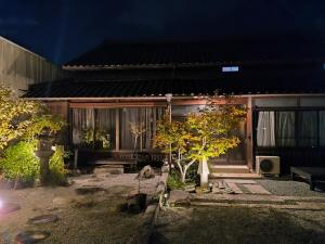 une maison avec une cour arborée devant elle dans l'établissement さぬきの宿 古民家 岡本, à Oda