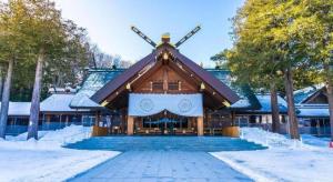 a large building with a sign on it in the snow at Sapporo Hotel Yamachi in Kotoni