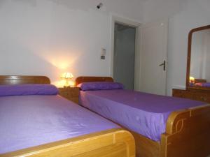 a bedroom with two beds with purple sheets and a mirror at Villa at Karawan Resort in Al Ḩammām
