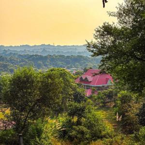 a house with a red roof in the middle of trees at Prakriti Farms in Rūpnagar