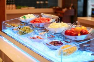 un buffet con tazones de frutas y hortalizas en un mostrador en Echarm Hotel Jinan West Station International Exhibition Center, en Jinan