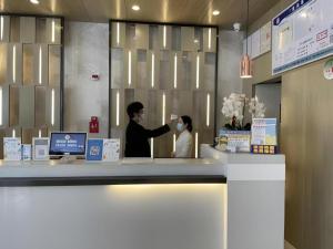 zwei Leute stehen an einem Tresen in einem Laden in der Unterkunft Echarm Hotel Kunming Railway Station Huancheng South Road Metro Station in Kunming