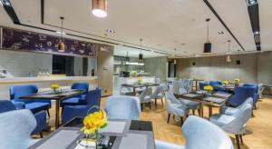 ein Restaurant mit blauen Stühlen und Tischen sowie einer Küche in der Unterkunft Echarm Hotel Nanning Baisha Avenue Tingjiang Interchange BBK in Nanning