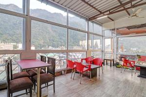 a room with red chairs and tables and windows at HOTEL O LAXMAN GRAND in Tapovan
