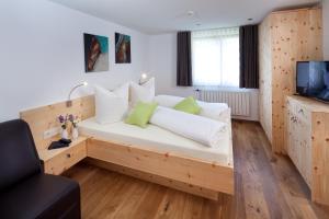 Zimmer mit einem Bett mit weißen Kissen und einem TV in der Unterkunft Aparthotel Brunnenhof in Damüls