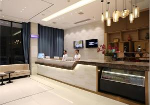 Dos personas de pie en un mostrador de recepción en el vestíbulo de un hotel. en City Comfort Inn Shaoyang Xinning, en Xinning