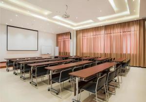 柳州にあるCity Comfort Inn Liuzhou Longtan Park Ma'anshan Baiyunのテーブルと椅子、プロジェクションスクリーン付きの教室