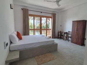 ein Schlafzimmer mit einem Bett und einem großen Fenster in der Unterkunft Blue Corals Beach Bungalow in Madihe East + 102 Fotos