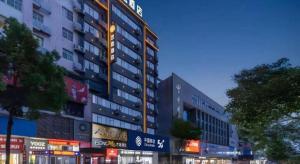 un edificio alto con letreros a un lado. en GreenTree Inn Shangrao Wuyishan Avenue Meide Yinxiang, en Shangrao