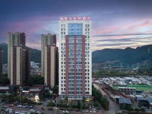 昆明市にあるThank Inn Hotel Yunnan Kunming Wuhua Puhuiyuanの都内の高い赤と白の建物