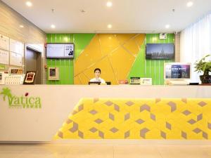 a man sitting at a counter in a store at Vatica Hotel Haikou Jinniuling Park Haizhiyuan in Haikou