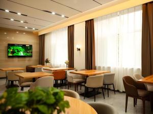 NingwuにあるShell Hotel Shanxi Xinzhou Wuning County Fengwu Squareのテーブルと椅子、薄型テレビのあるレストラン