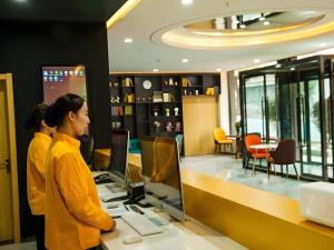 NingwuにあるShell Hotel Shanxi Xinzhou Wuning County Fengwu Squareのコンピューターを持ってカウンターの前に立っている2人の女性