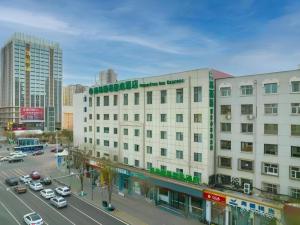un gran edificio blanco en una calle de la ciudad con coches en GreenTree Inn Express Datong High-Speed Railway Station Old City Wall, en Datong
