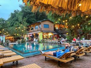 a group of people laying on chairs by a pool at Tam Coc Central Bungalow-Ninh Binh in Vũ Lâm