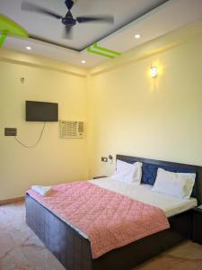 a bedroom with a bed with a tv on the wall at Hotel Pleasure Inn in Prayagraj